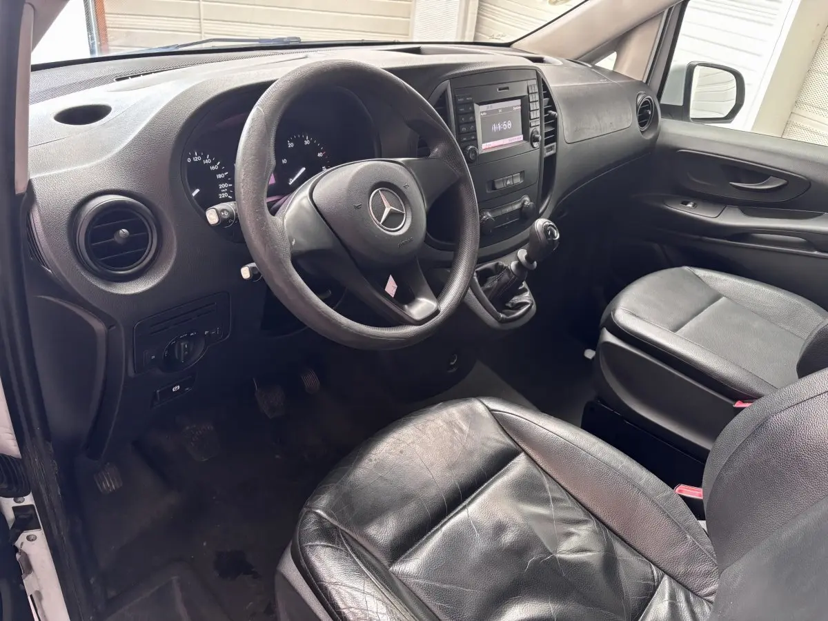 Vue intérieure côté conducteur du Mercedes Vito 111 CDI 2016, volant cuir, sièges noirs et tableau de bord avec écran central.