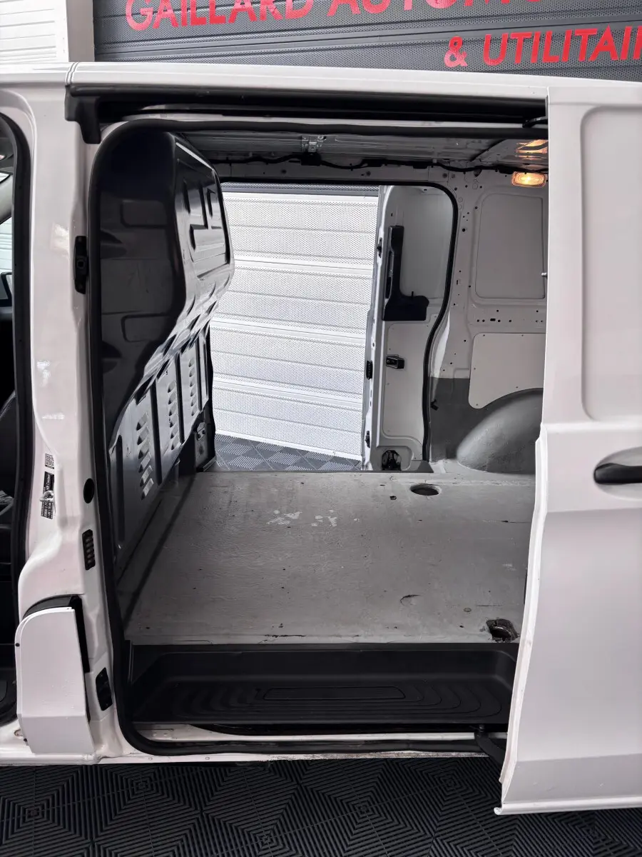 Vue intérieure du compartiment de chargement du Mercedes Vito 111 CDI Compact blanc, porte latérale ouverte.