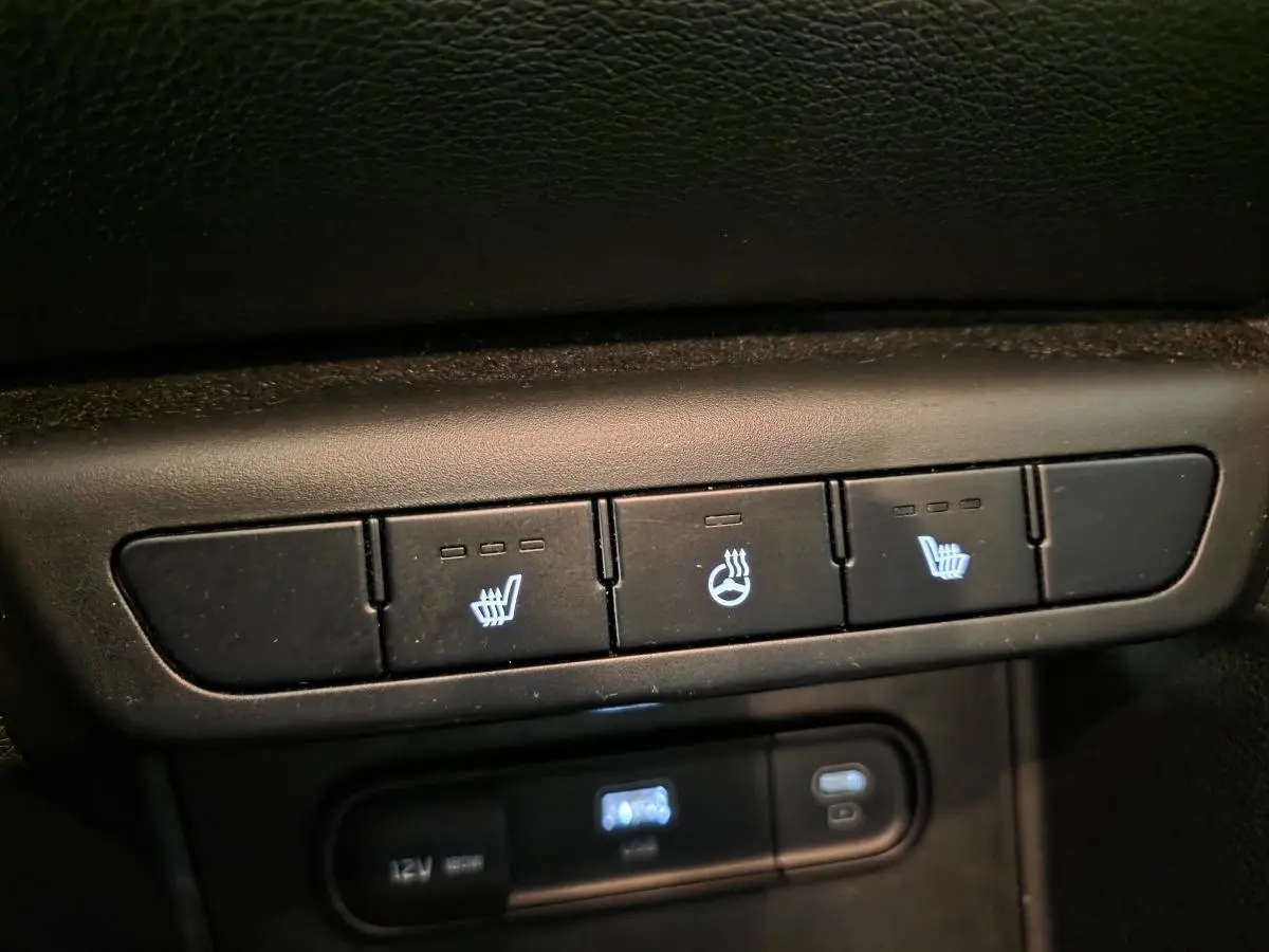 Gros plan sur les commandes de sièges chauffants et volant chauffant du Kia Sportage noir 2022.