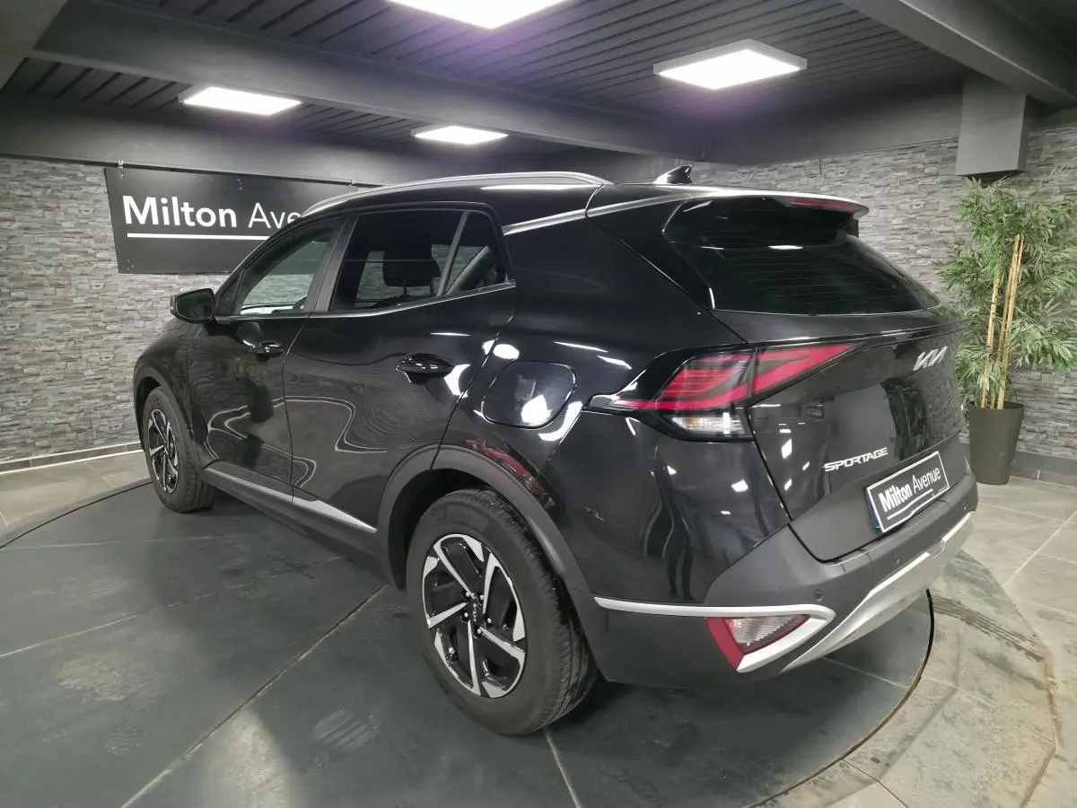 Vue 3/4 arrière droite du KIA SPORTAGE noir avec feux arrière LED et jantes alliage 17 pouces en showroom.