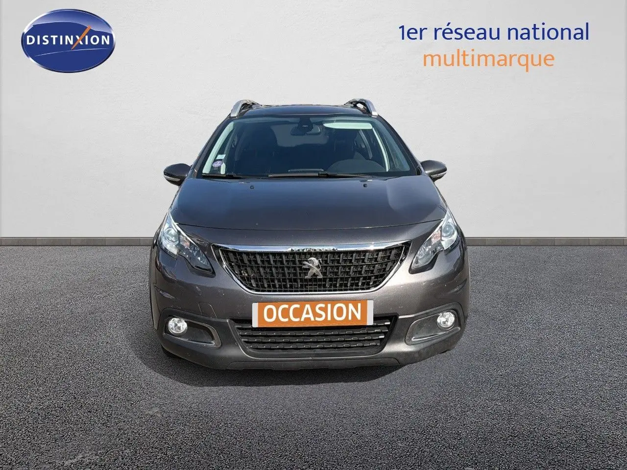 Vue frontale d'un Peugeot 2008 gris platinium 2019 avec calandre noire et phares allumés.