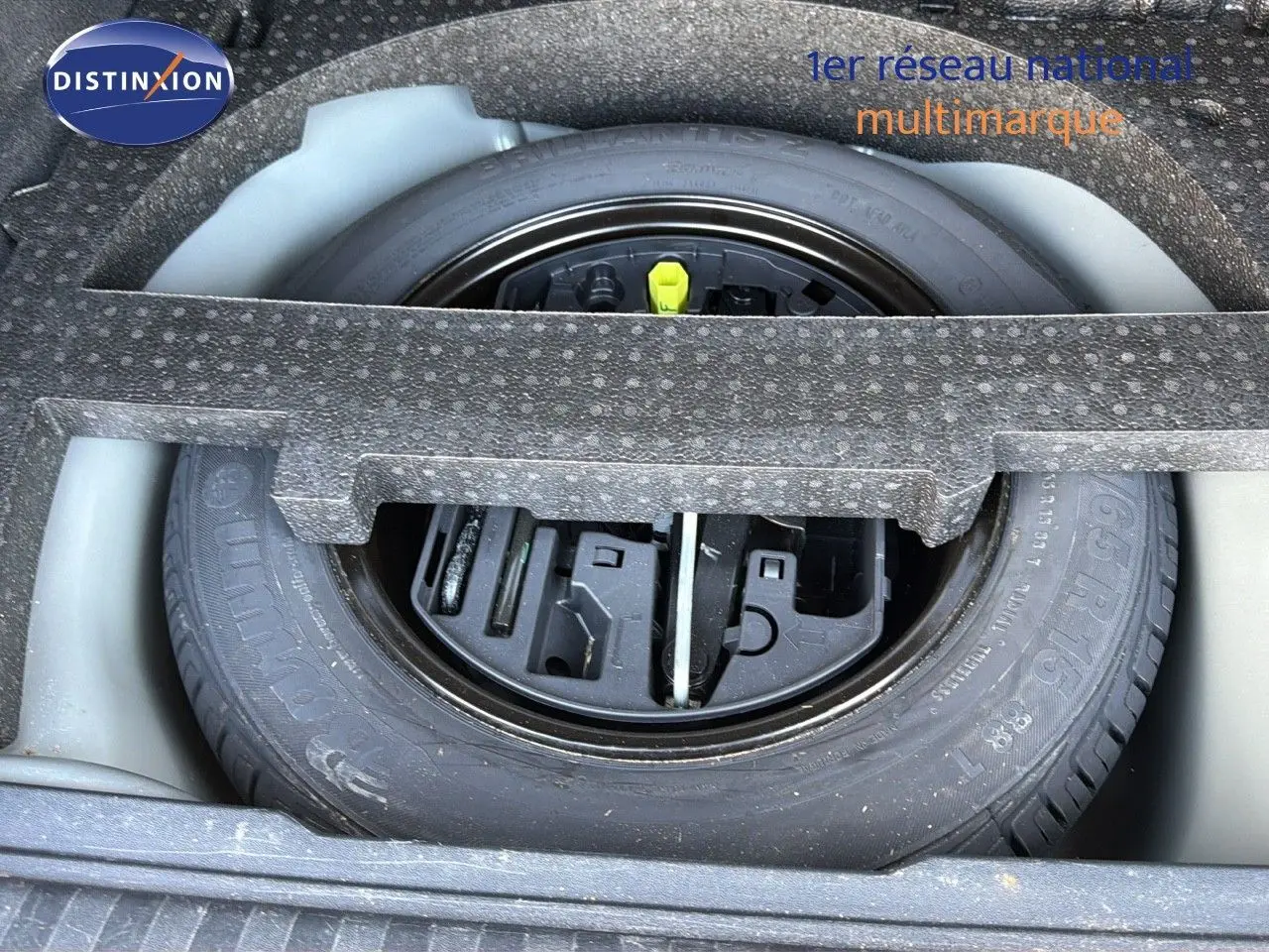 Roue de secours et kit de réparation logés dans le coffre d'une Peugeot 2008 gris platinium vue de dessus.