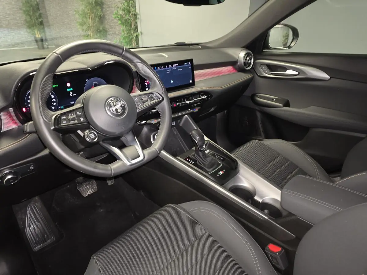 Vue intérieure côté conducteur de l'Alfa Romeo Tonale 1.3 PHEV 2023 avec tableau de bord digital et sellerie noire carbone.