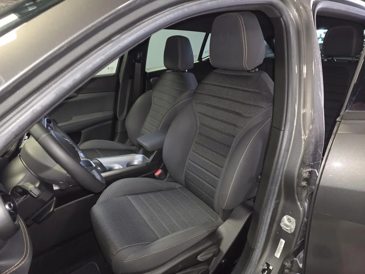 Vue intérieure côté conducteur de l'Alfa Romeo Tonale gris, mettant en valeur les sièges AlfaTec noirs avec surpiqûres beige.