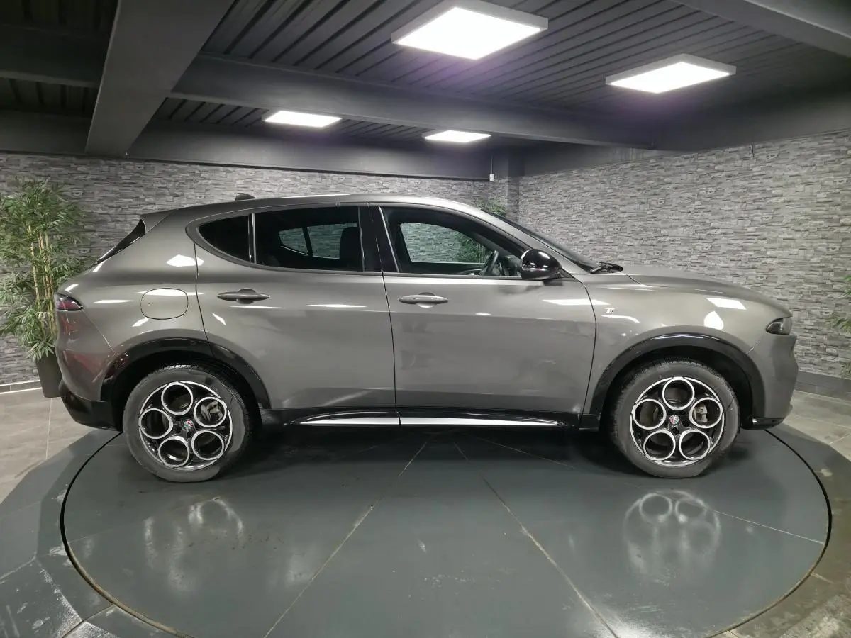 Vue de profil côté gauche d'un Alfa Romeo Tonale gris métallisé 2023 avec jantes alliage 18 pouces et rétroviseurs noirs brillants.
