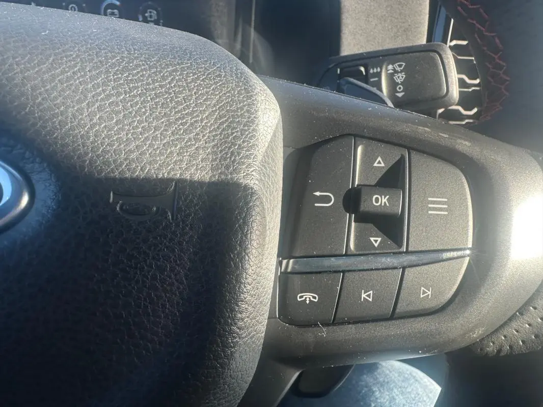 Gros plan sur le volant noir du Ford Ranger 2025 avec commandes multifonctions et logo Ford visible.