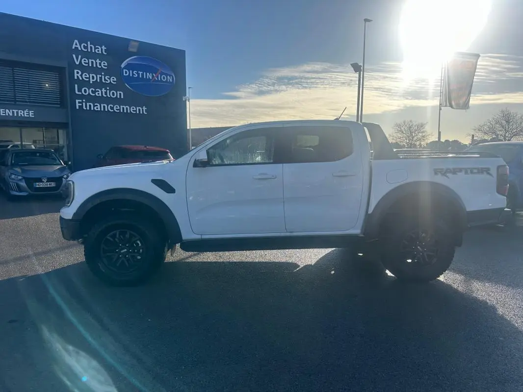 Ford Ranger Raptor blanc en profil gauche, avec jantes alliage noires et marquage RAPTOR sur la benne.