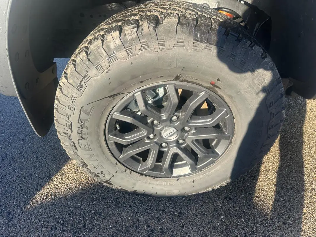 Gros plan sur la roue avant gauche du Ford Ranger Raptor 2025, jante alliage noire et pneu tout-terrain.