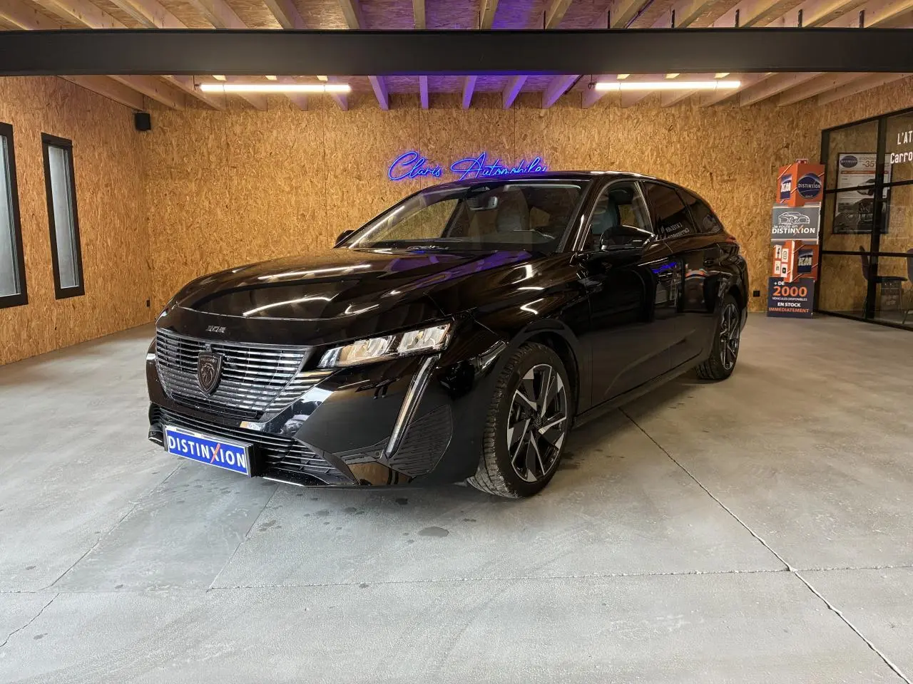 Peugeot 308 SW noire vue en 3/4 avant droit dans un showroom avec éclairage intérieur.
