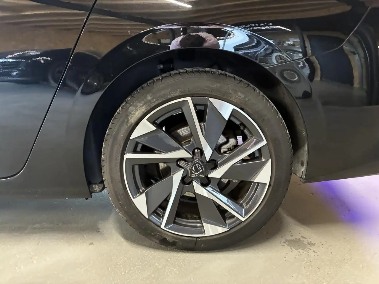 Gros plan sur la roue arrière droite de la Peugeot 308 SW noire 2024 avec jante alliage 17'' Halong diamantée.