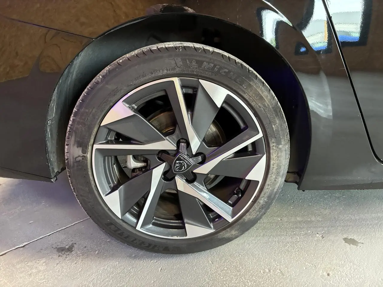 Gros plan sur la jante alliage 17'' Halong diamantée noire et argentée d’une Peugeot 308 SW noire, côté arrière droit.