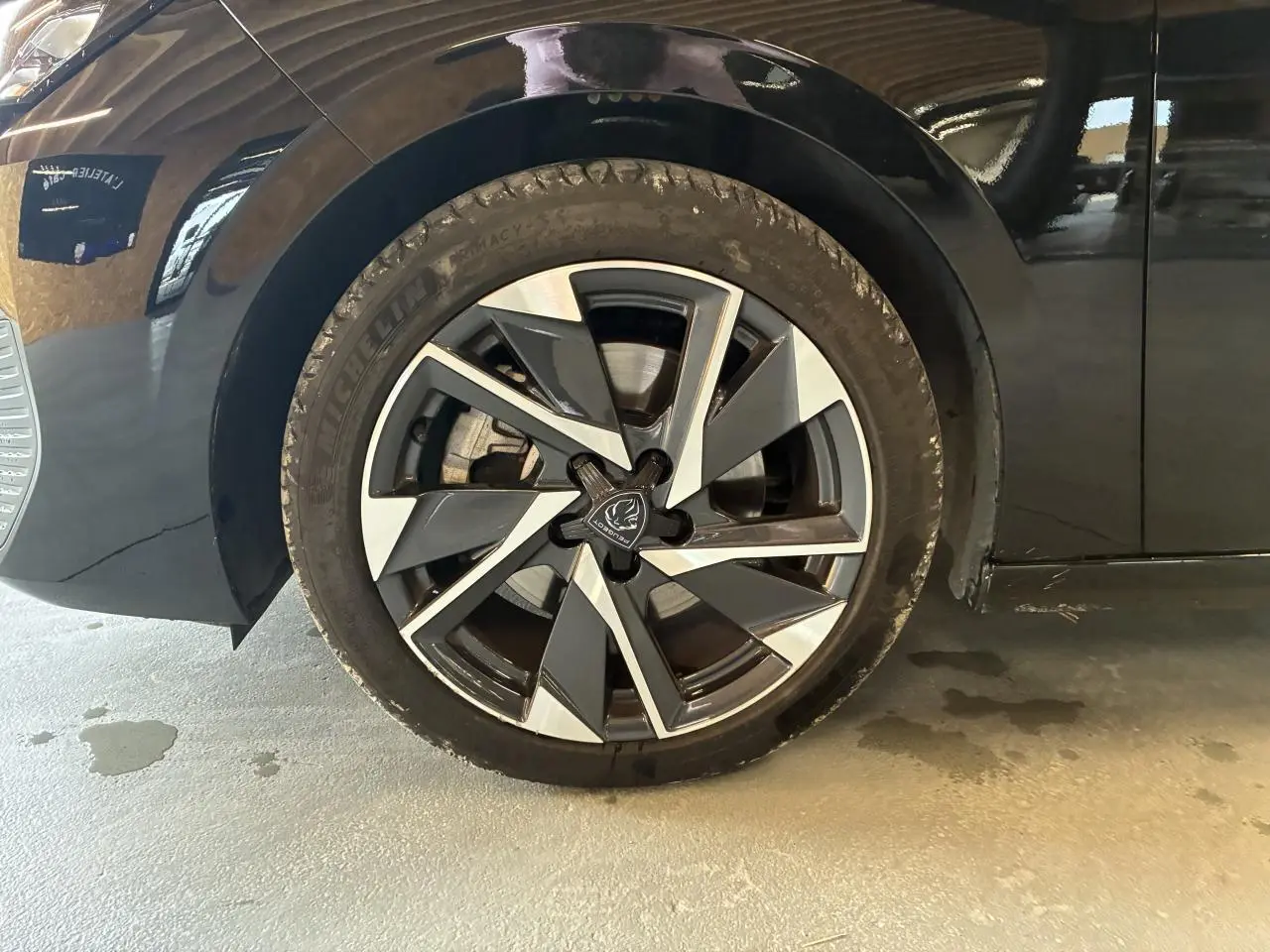 Gros plan sur la roue avant gauche noire avec jante alliage 17'' Halong diamantée du Peugeot 308 SW 2024.