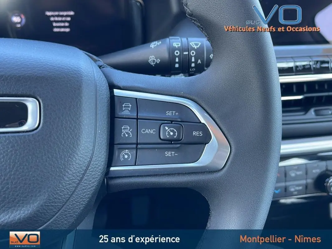 Gros plan sur le volant du Jeep Compass 2024 montrant les commandes du régulateur de vitesse et la finition noire texturée.