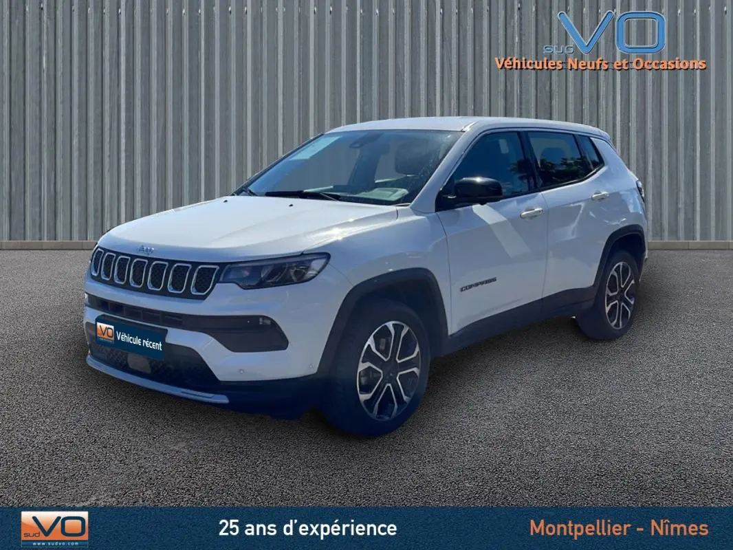 Jeep Compass blanc vue 3/4 avant droit, jantes alliage 18 pouces et rétroviseurs noirs sur fond urbain.
