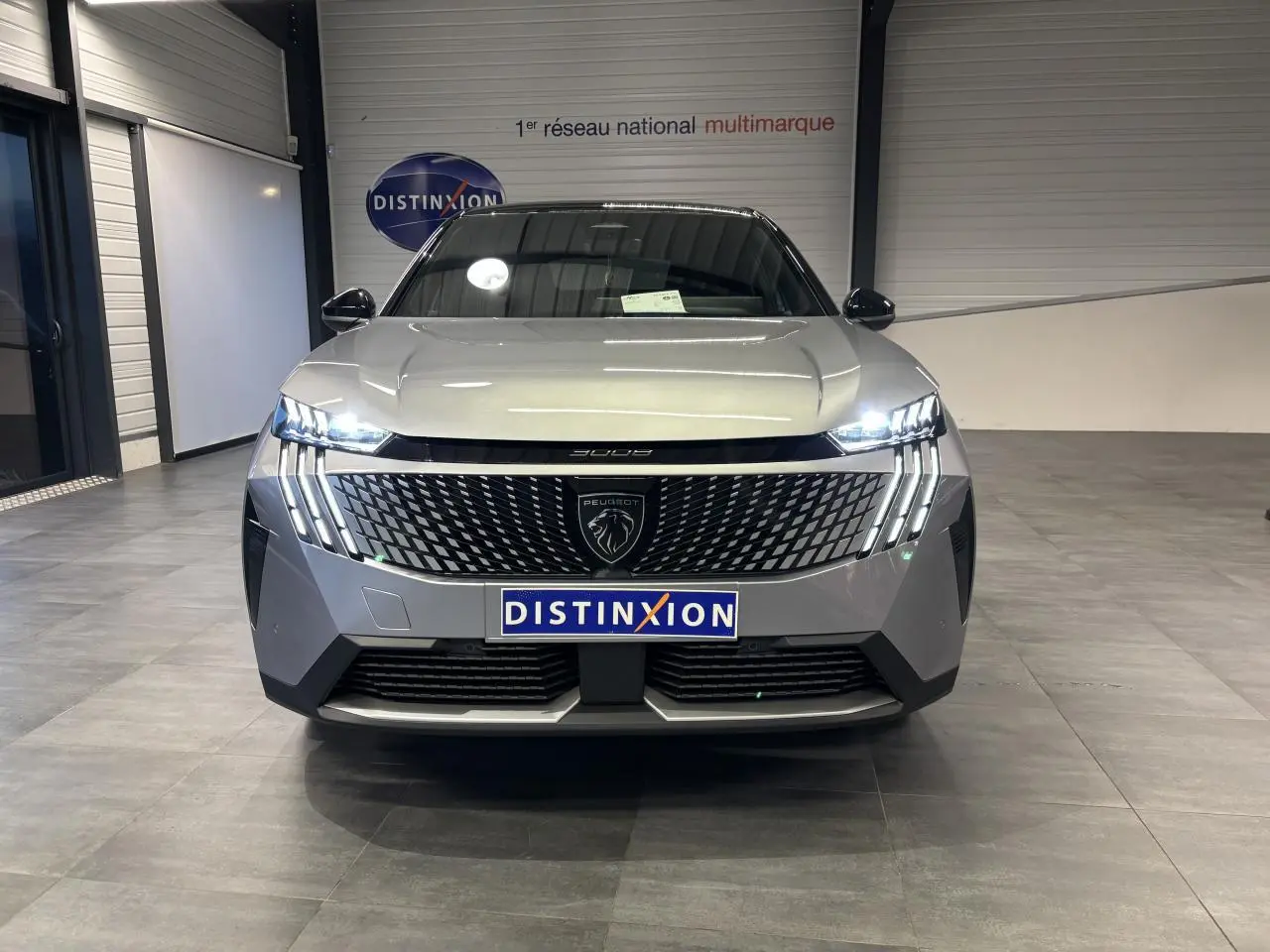 Vue de face du Peugeot 3008 gris Artense avec calandre noire à motif 3D et feux LED griffes allumés.