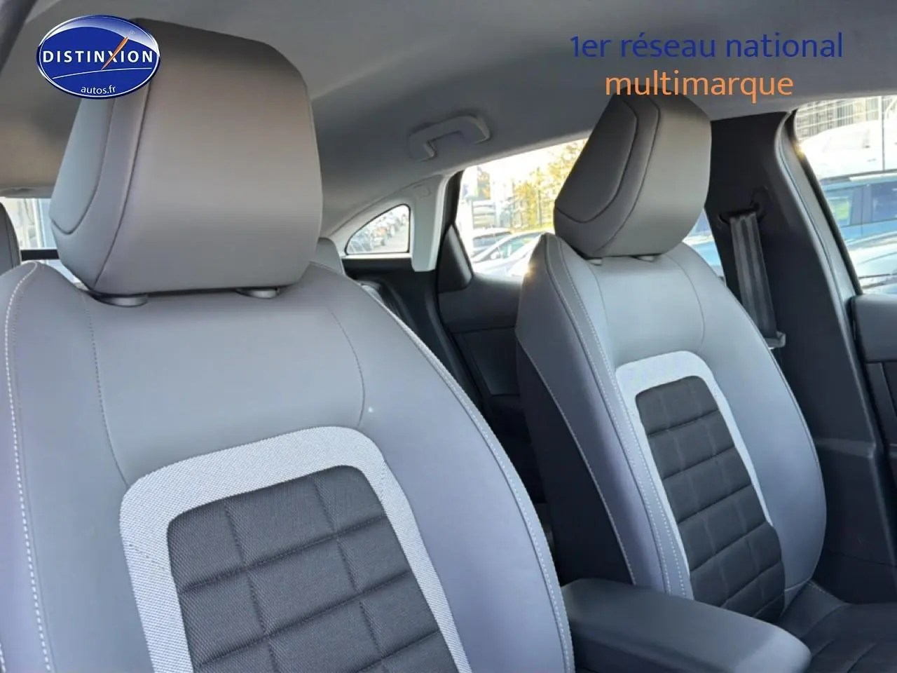 Gros plan sur les sièges avant gris clair et noir de la Citroën C4 électrique 2025, avec accoudoir central visible.
