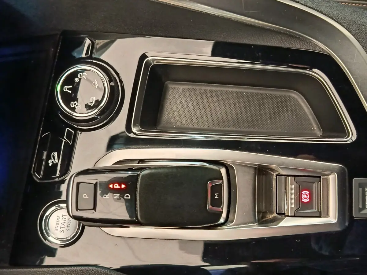 Gros plan sur la console centrale noire brillante du Peugeot 5008 2019, avec levier de vitesse automatique et bouton start/stop.