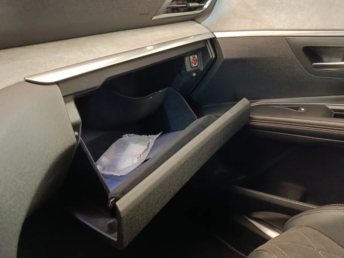 Intérieur côté passager du Peugeot 5008 gris clair, boîte à gants ouverte avec rangement visible.