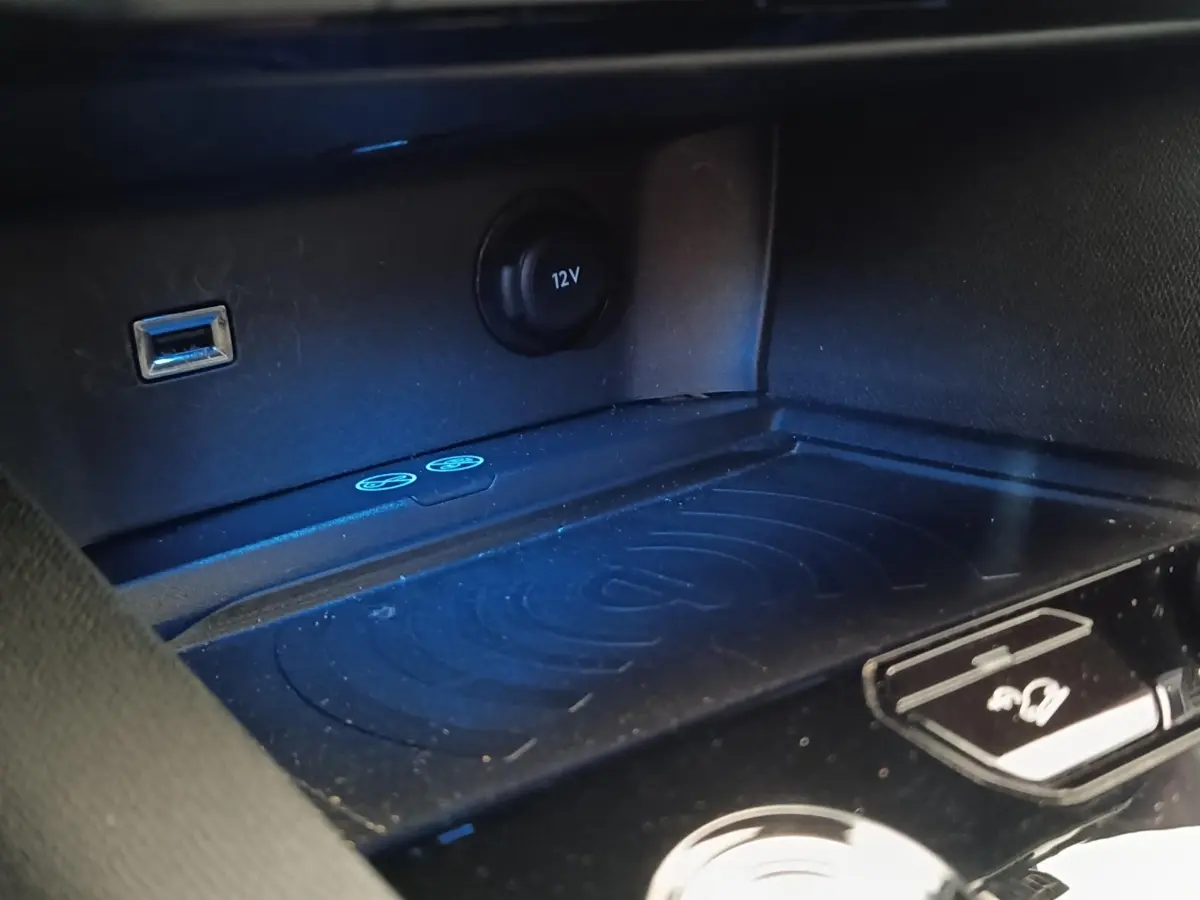 Gros plan sur la console centrale noire du Peugeot 5008 2019 avec prise USB, prise 12V et zone de charge sans fil.