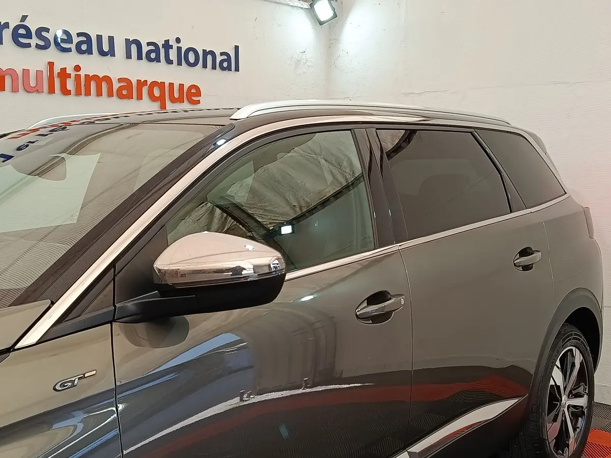 Vue latérale droite d’un Peugeot 5008 GT gris clair avec rétroviseur chromé et jantes distinctives.