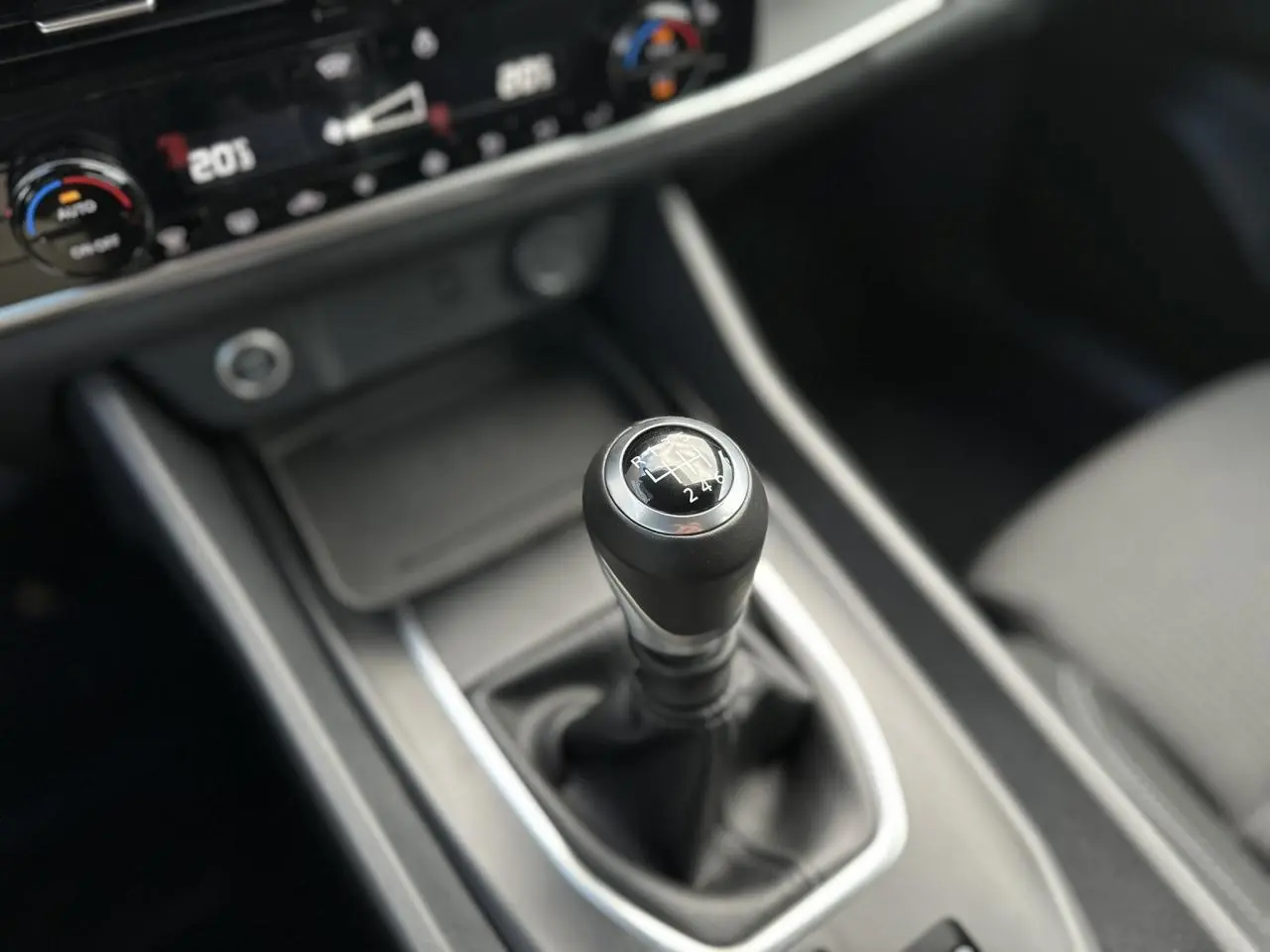 Gros plan sur le levier de vitesses manuel noir du Nissan Qashqai 2025, avec console centrale et commandes de climatisation visibles.