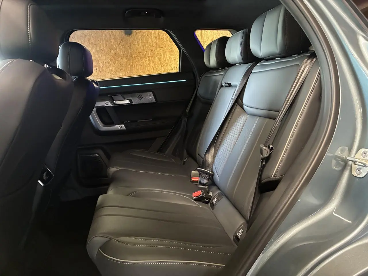 Vue intérieure côté droit des sièges arrière en cuir noir du SUV JAECOO J7 2026, avec ceinture de sécurité et éclairage d'ambiance.