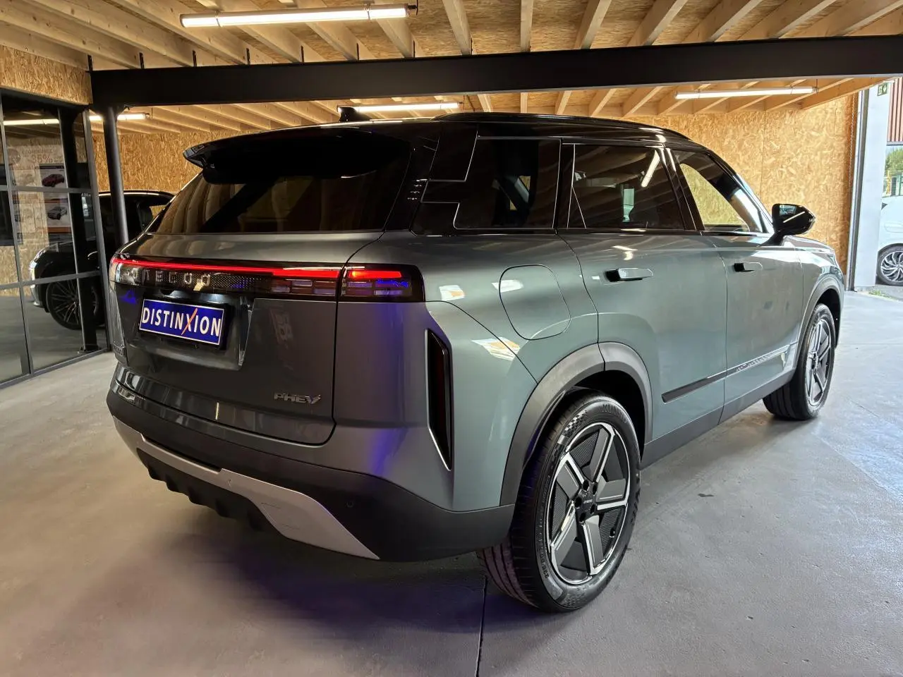Vue 3/4 arrière droite du SUV JAECOO J7 gris olive avec toit noir et feux arrière LED continus en intérieur.