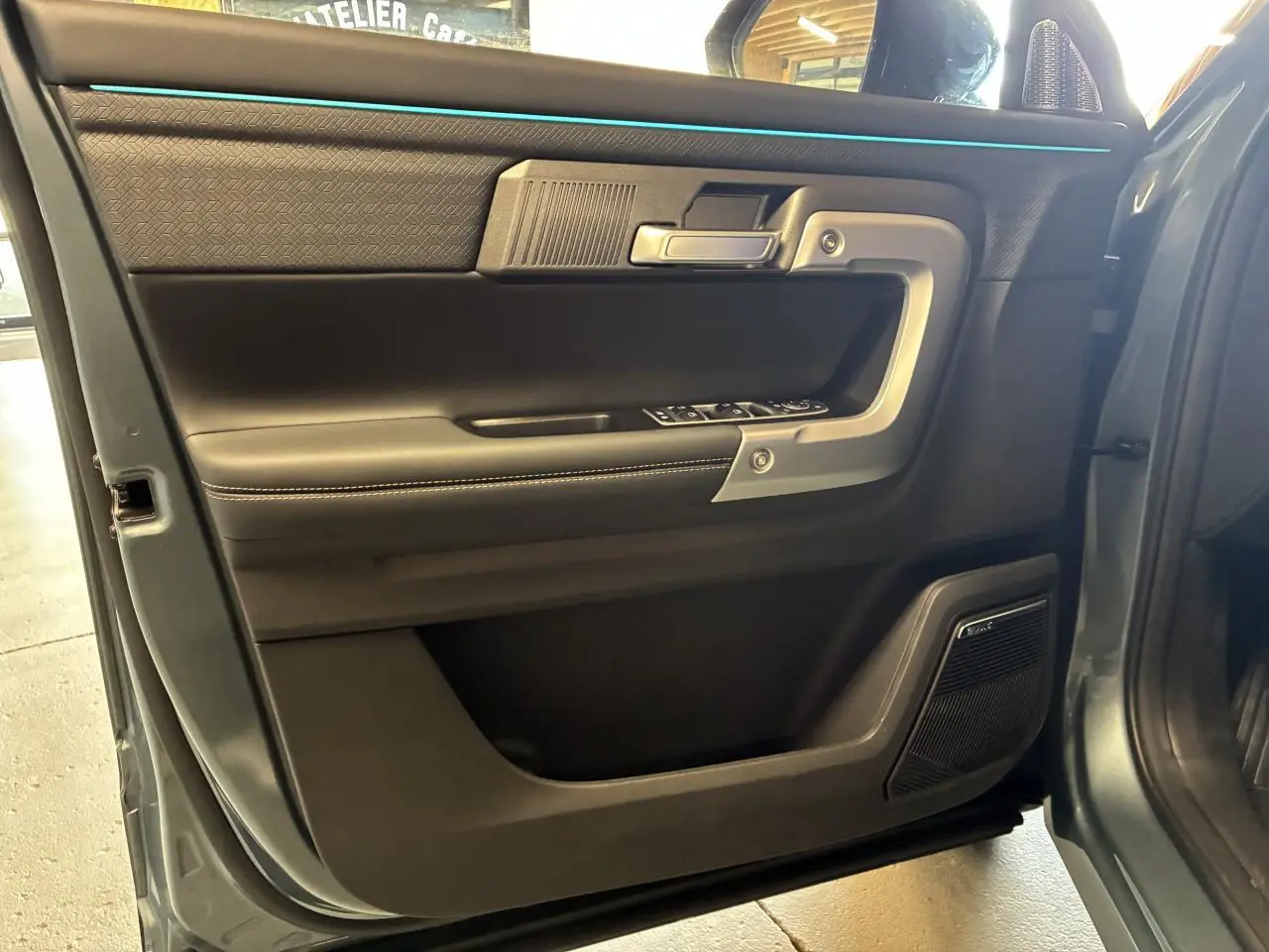 Vue rapprochée de la porte avant gauche du JAECOO J7 gris olive, avec garniture noire et haut-parleur Sony intégré.