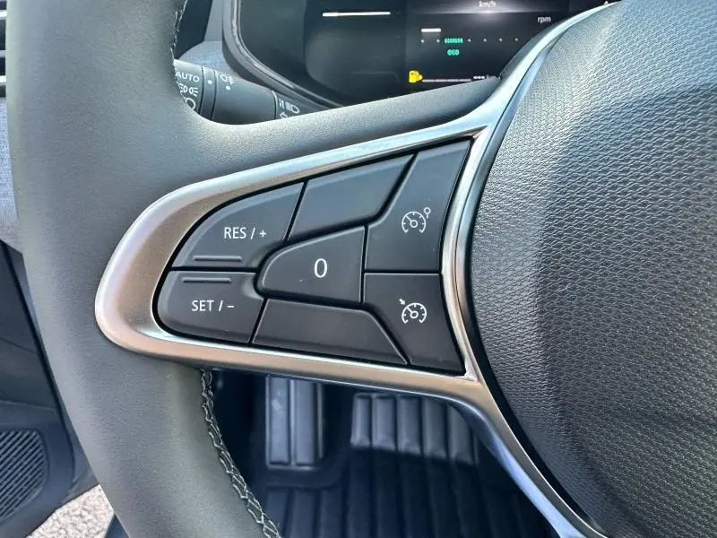 Gros plan sur les commandes du régulateur de vitesse au volant d'une Renault Clio 2025, intérieur noir.