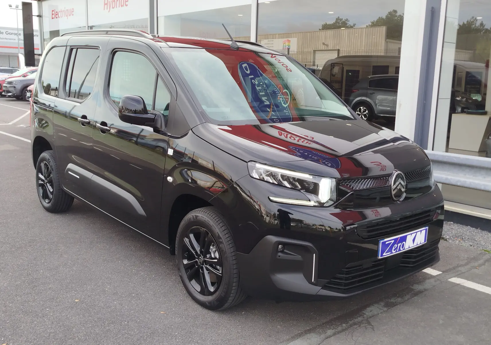 Vue 3/4 avant droite d'un Citroën Berlingo noir Perla Nera avec jantes noires et calandre distinctive.