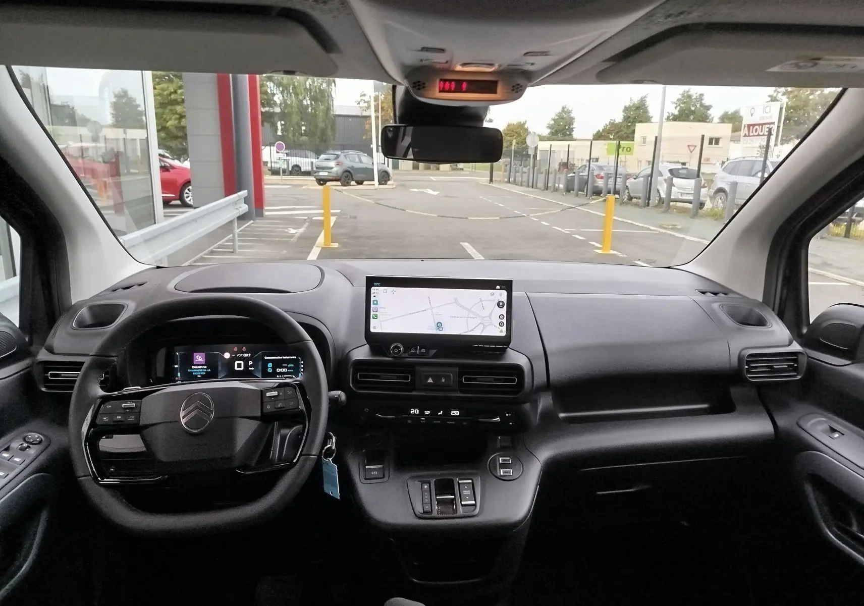 Vue intérieure du tableau de bord et volant du Citroën Berlingo 2025 noir, avec écran tactile central et commandes au volant.