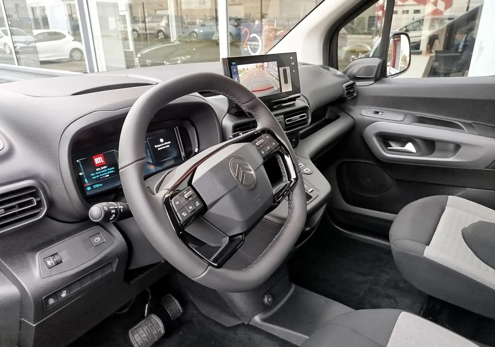 Intérieur du Citroën Berlingo 2025 vu côté conducteur, volant multifonction et écran central affichant la caméra de recul.