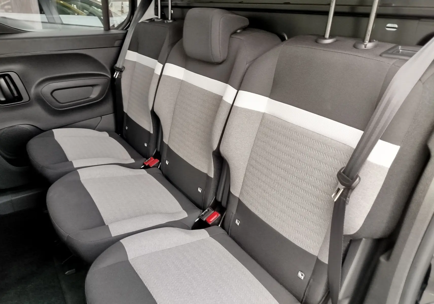 Vue latérale intérieure des sièges arrière gris clair et foncé du Citroën Berlingo 2025, version Plus+Pack Style.