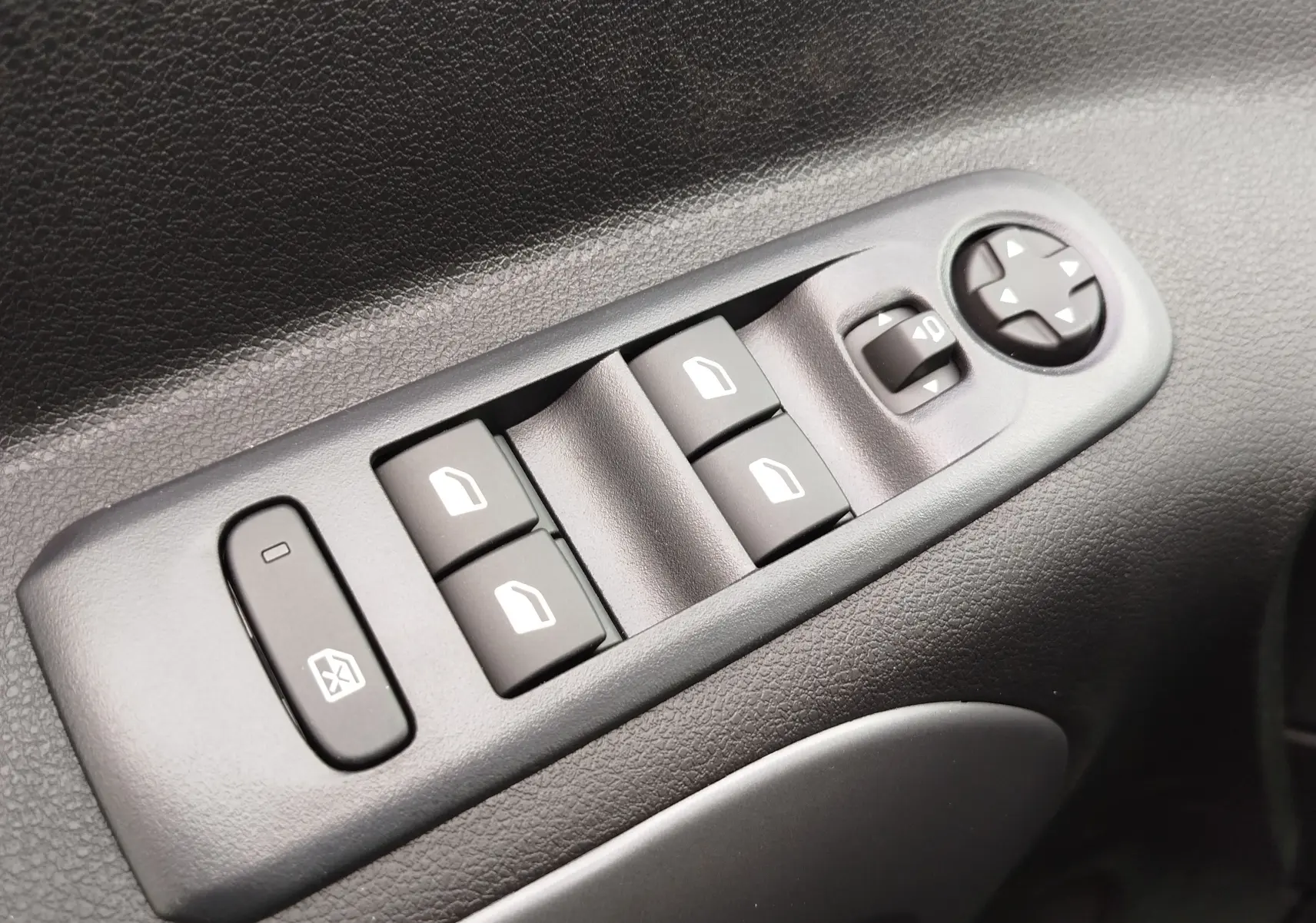 Gros plan sur les commandes électriques des vitres et rétroviseurs côté gauche d'un Citroën Berlingo noir Perla Nera 2025.