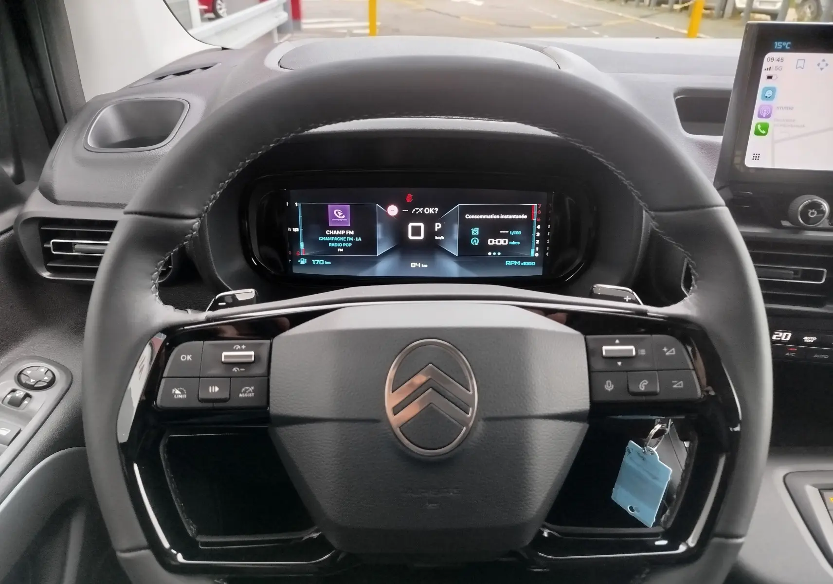 Vue rapprochée du volant noir de la Citroën Berlingo 2025 avec commandes intégrées et tableau de bord numérique allumé.