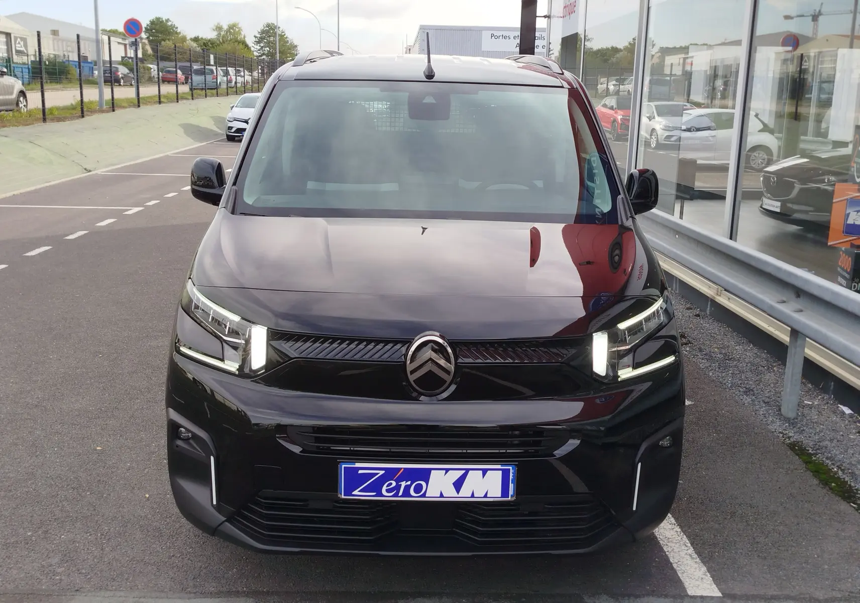 Vue avant d'un Citroën Berlingo noir Perla Nera avec feux LED allumés sur un parking extérieur.