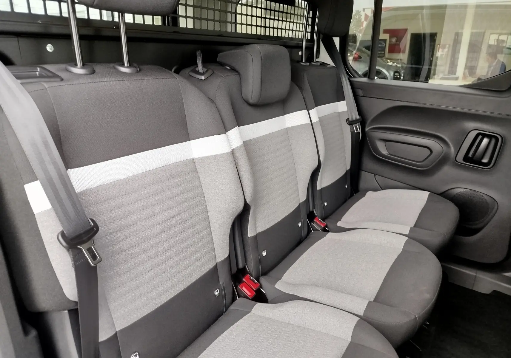Vue intérieure du siège arrière gris clair et noir du Citroën Berlingo 2025 avec séparation métallique derrière les sièges.