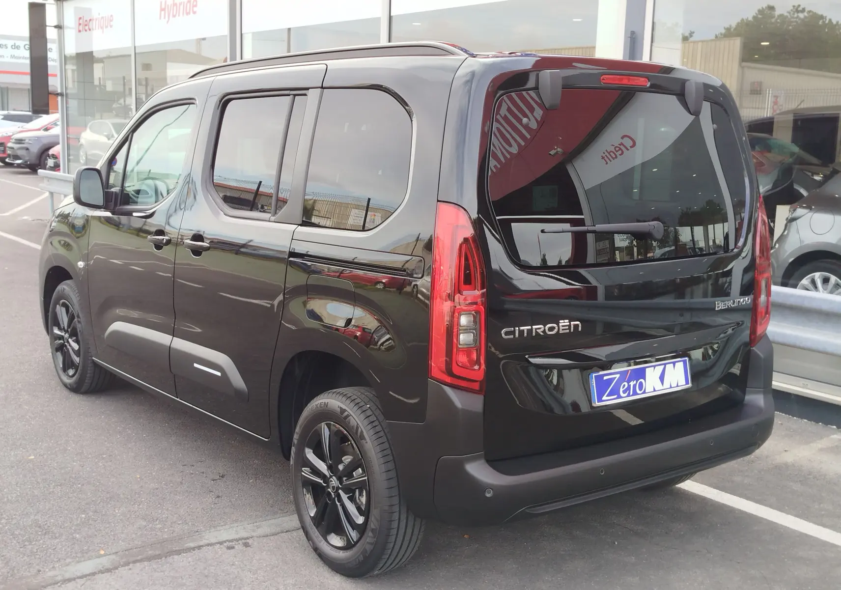 Vue 3/4 arrière droite d'un Citroën Berlingo noir Perla Nera métallisé avec vitres teintées et jantes noires.