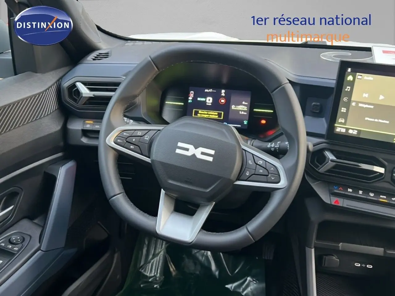 Vue intérieure centrée sur le volant multifonction et le tableau de bord numérique du Dacia Duster blanc Glacier 2025.