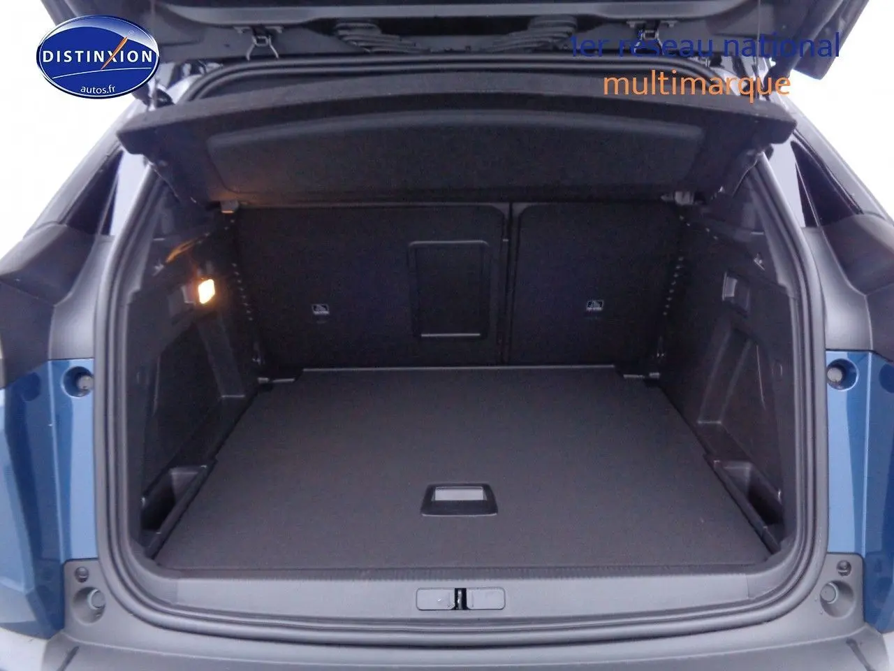 Coffre ouvert en vue arrière d’un Peugeot 3008 2023 bleu Celebes Metal, montrant un espace de chargement spacieux et bien éclairé.