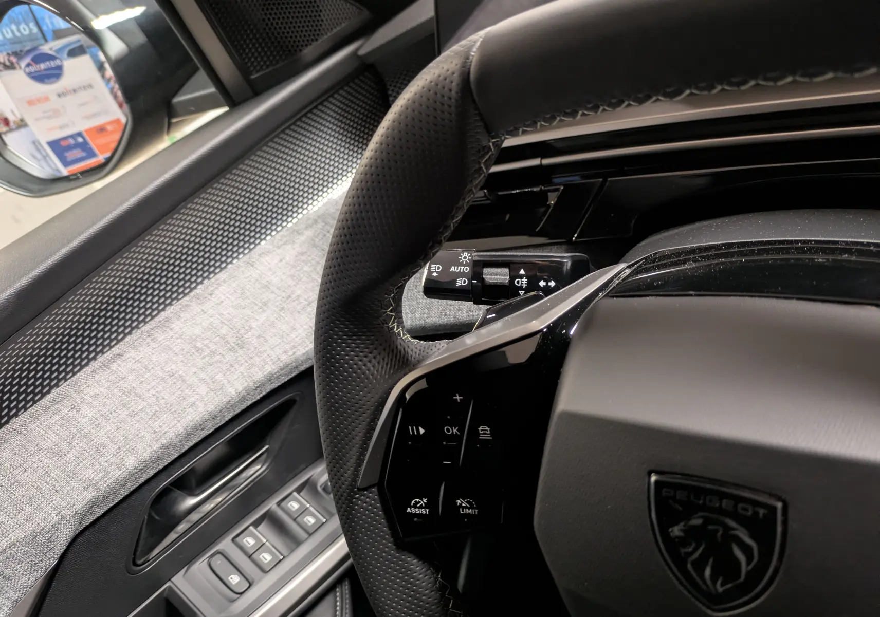 Vue intérieure rapprochée du volant noir perforé et des commandes surpiquées du Peugeot 3008 Hybrid 145 GT 2025.