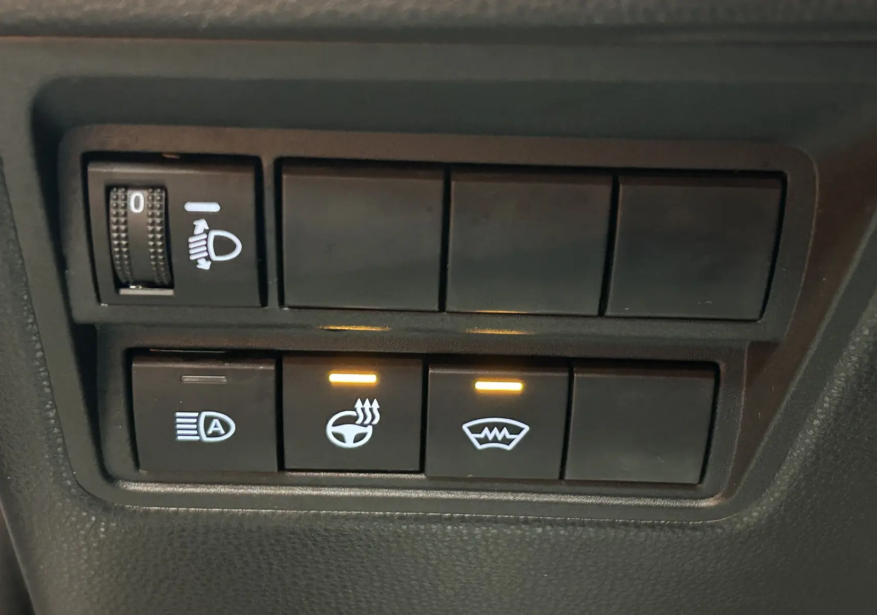 Gros plan sur les boutons de commande du volant et pare-brise chauffants dans une Toyota Yaris Cross gris minéral.