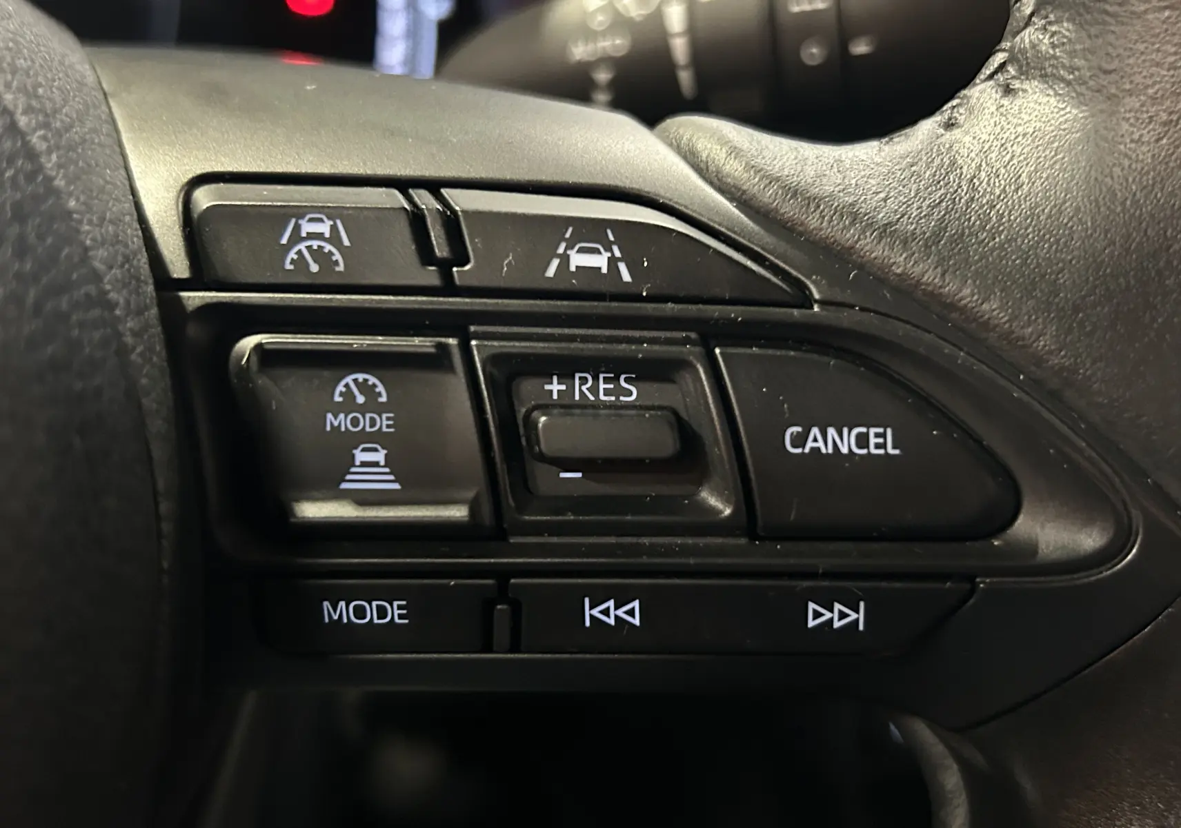 Gros plan sur les commandes au volant côté droit de la Toyota Yaris Cross 2025, boutons de régulateur et assistances visibles.