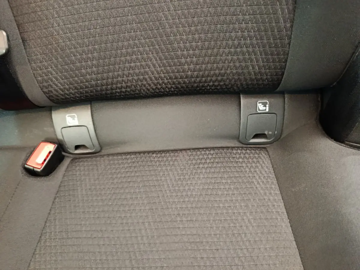 Détail de la banquette arrière noire du Nissan Qashqai 1.3 MHEV avec fixations Isofix et boucle de ceinture rouge visible.