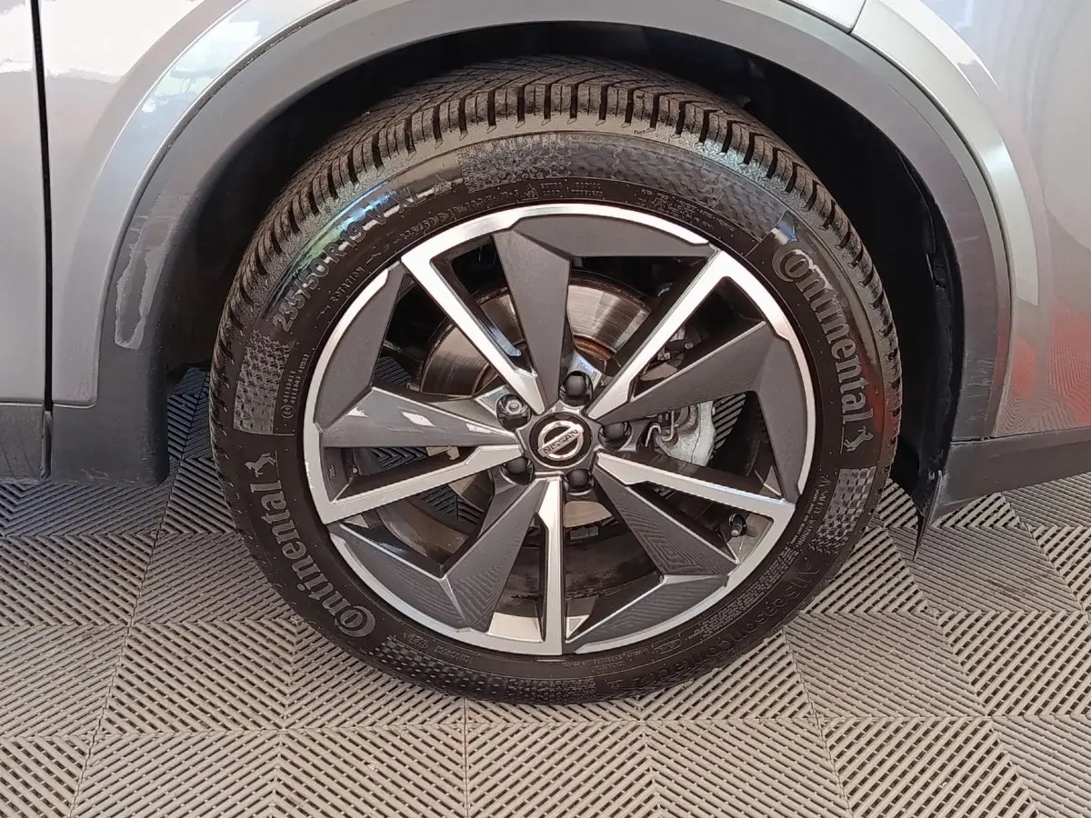 Gros plan sur la roue avant gauche du Nissan Qashqai gris foncé, avec jante alliage bicolore et pneu Continental.
