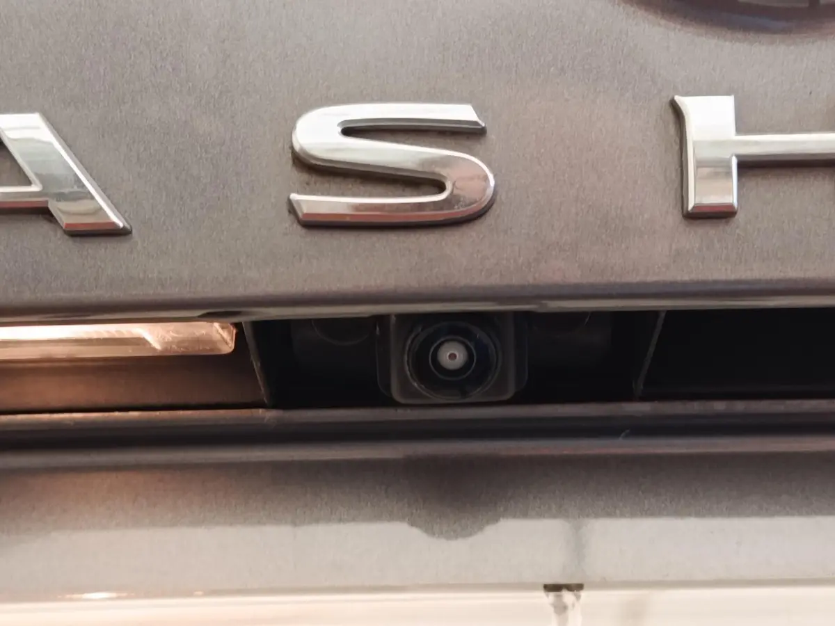 Gros plan sur la caméra de recul intégrée sous le logo arrière gris foncé du Nissan Qashqai 2022.