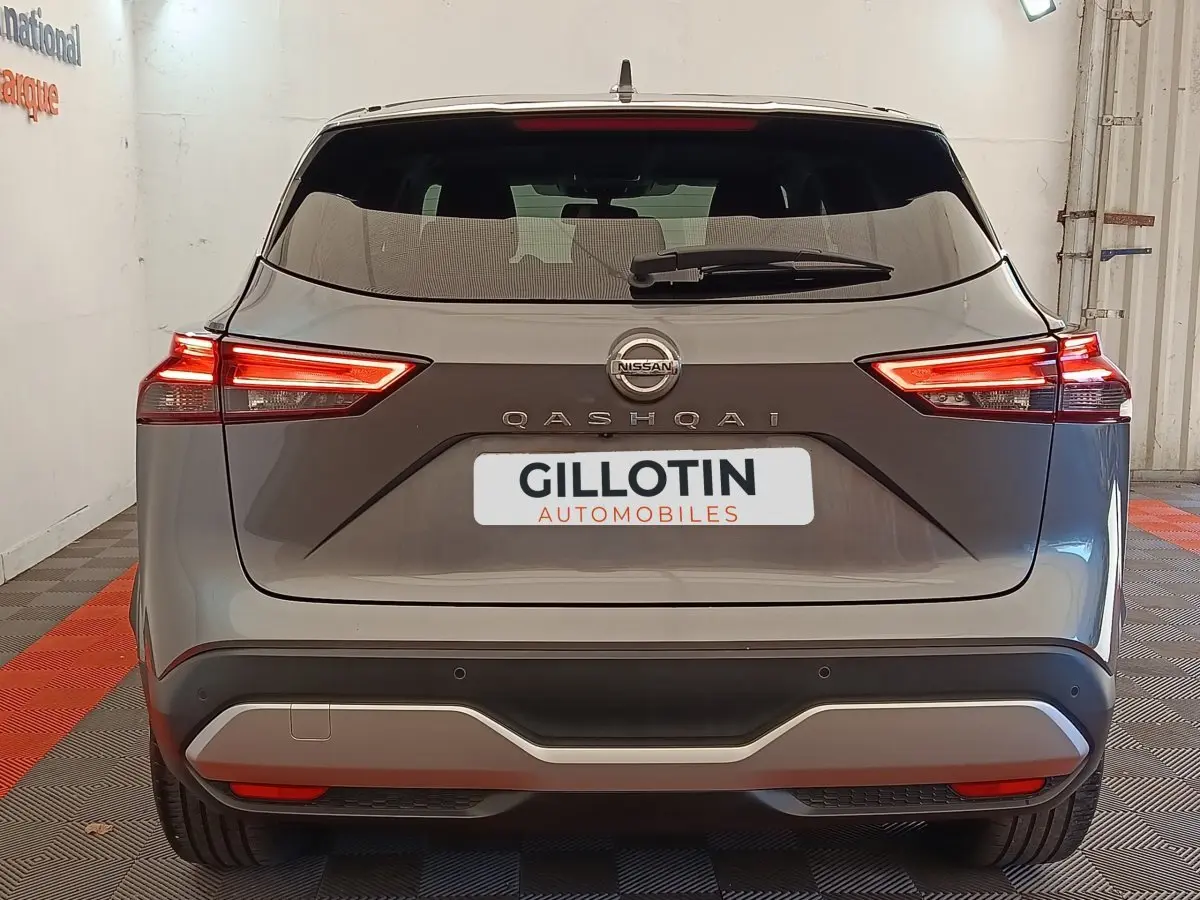 Vue arrière d'un Nissan Qashqai gris foncé 2022 avec feux LED allumés dans un showroom.