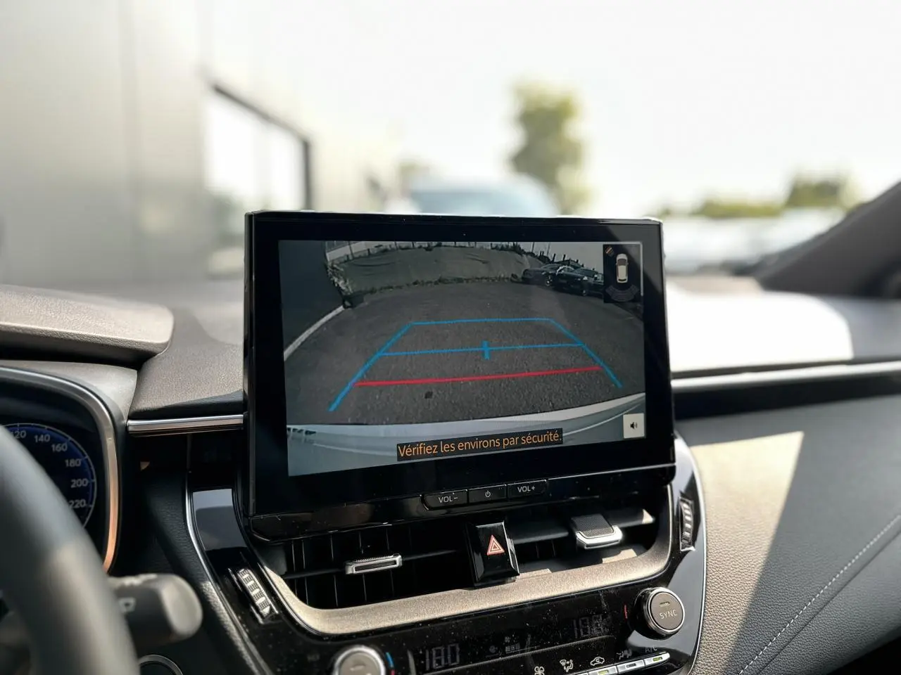 Écran multimédia affichant la caméra de recul dans l’habitacle d’une Toyota Corolla Touring Sport blanche.
