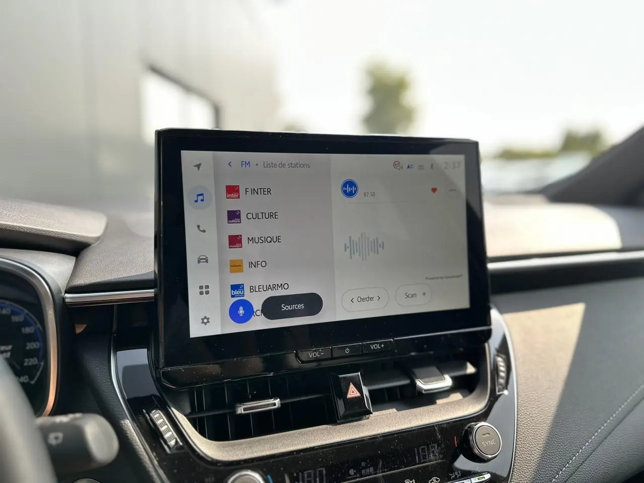 Écran tactile multimédia au centre du tableau de bord de la Toyota Corolla Touring Sport blanche 2025.