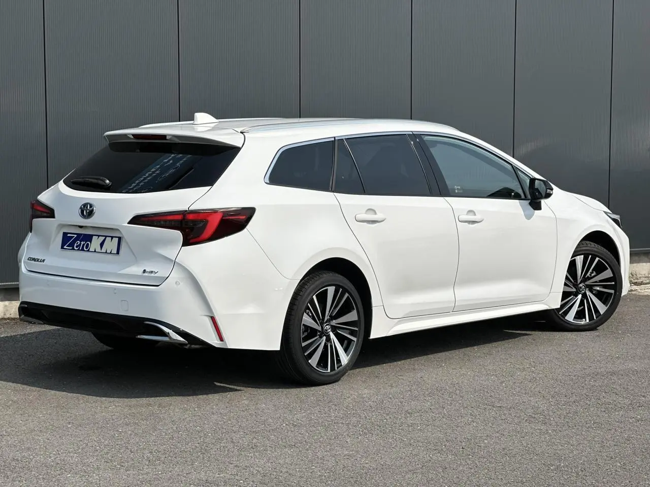 Toyota Corolla Touring Sport blanc Neige vue 3/4 arrière droit avec jantes alliage et vitres surteintées.